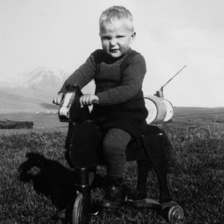 Pistilshöfundur á Blesa á hlaðinu í Garðshorni, hlanddælan í baksýn á bak við bensínfötin. Vinstra megin við snoppuna á Blesa sést í gömul fjárhús.